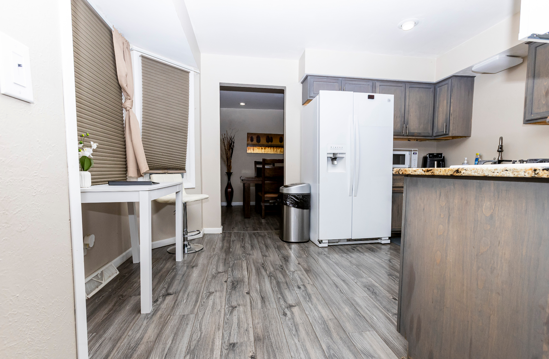 Kitchen with workspace nook, side-by-side fridge, and open flow to the dining room