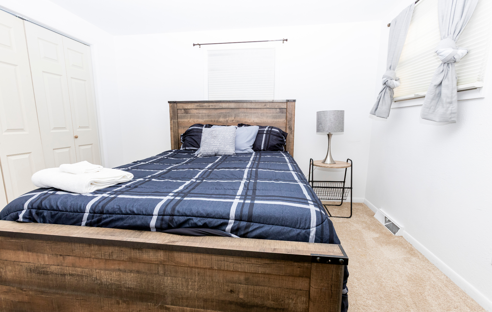 Bedroom with rustic wood queen bed, plaid bedding, and bright natural light