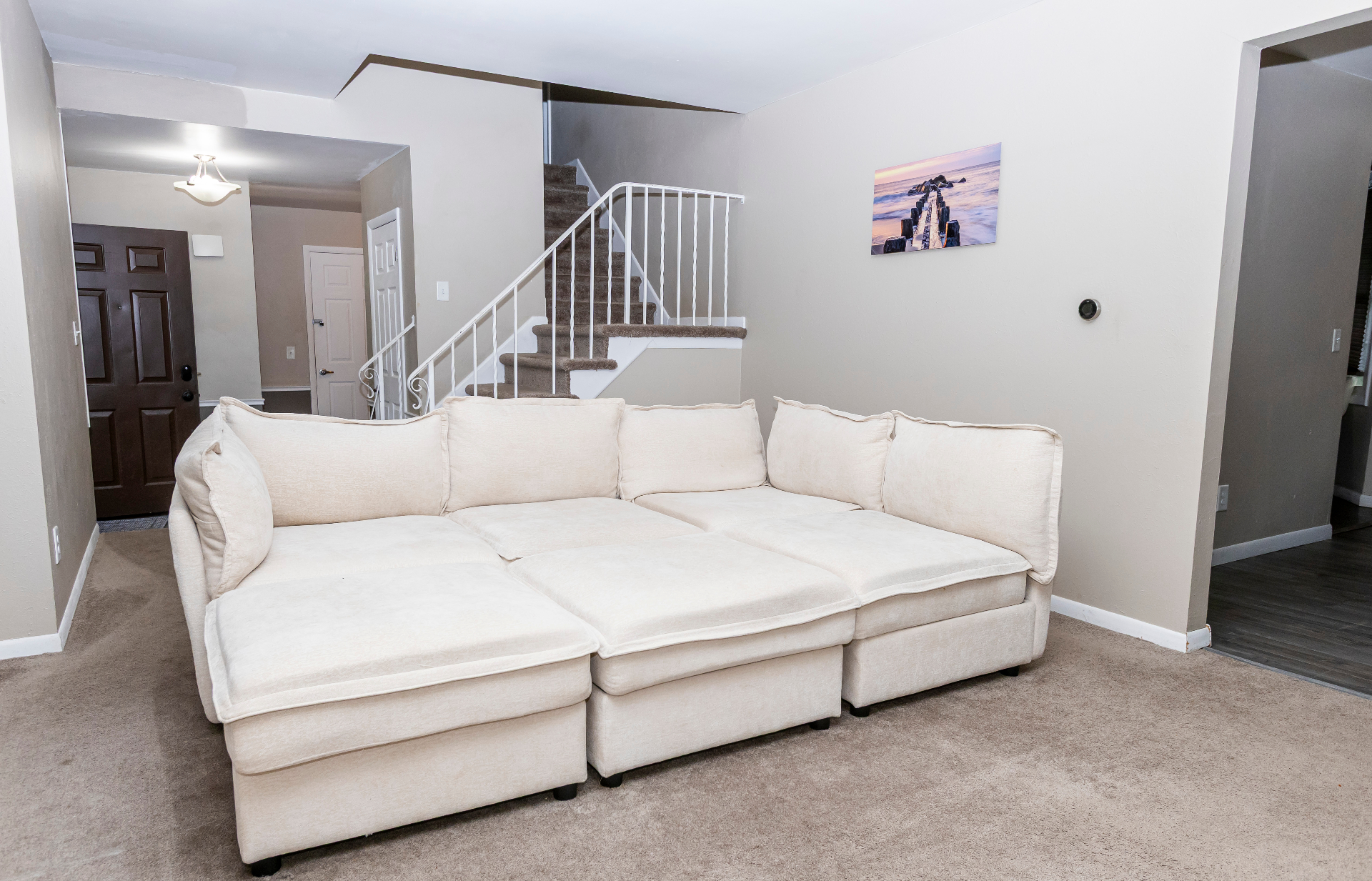 Spacious lower-level lounge with modular cream sectional and staircase
