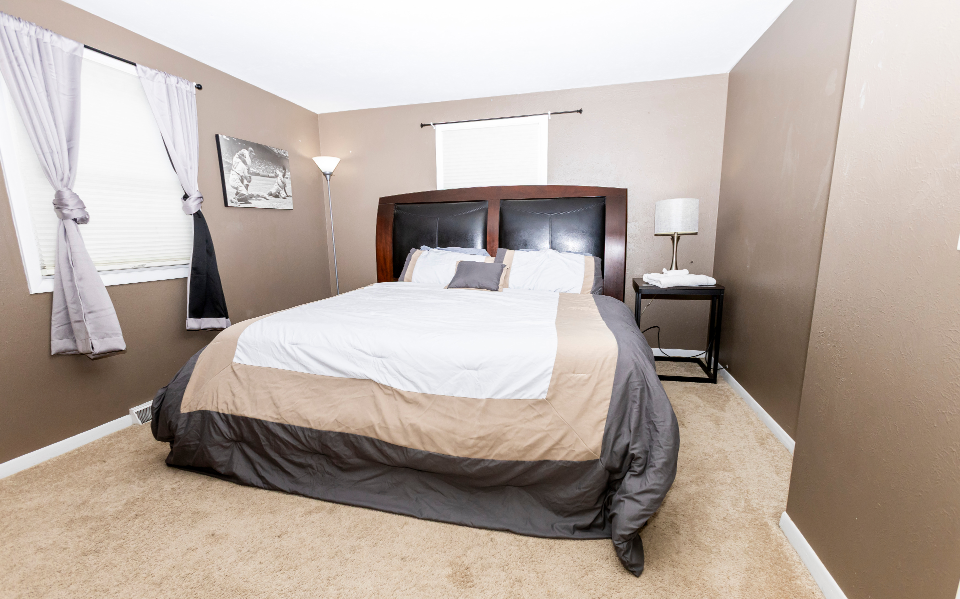 Second bedroom with queen bed, dark leather headboard, and vintage baseball print